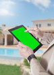 Mani e tablet con sfondo verde e villa