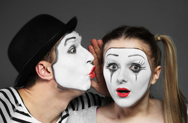 Male mime sharing secret with surprised female mime