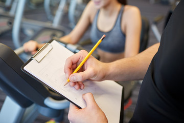 Canvas Print - close up of trainer hands with clipboard in gym