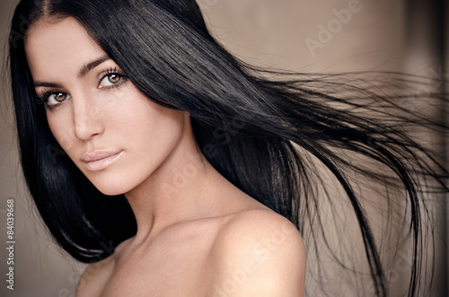 Naklejka dekoracyjna Dramatic portrait of a girl theme: portrait of a beautiful lonely girl with flying hair in the wind isolated on dark background in studio