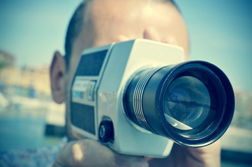 young man filming with a retro film camera