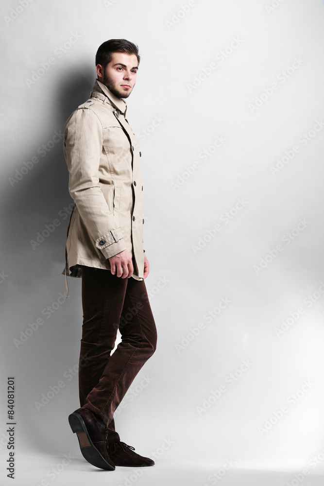 Young man in coat on gray background