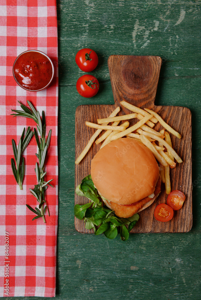 Hamburger, french fries and vegetables on wooden table top view