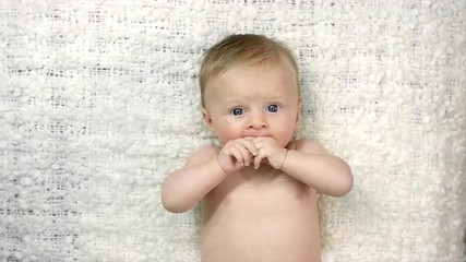 birds eye view of a baby laying on its back and sucking its hand