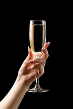 Female Hand With Champagne Glass On Black Background.