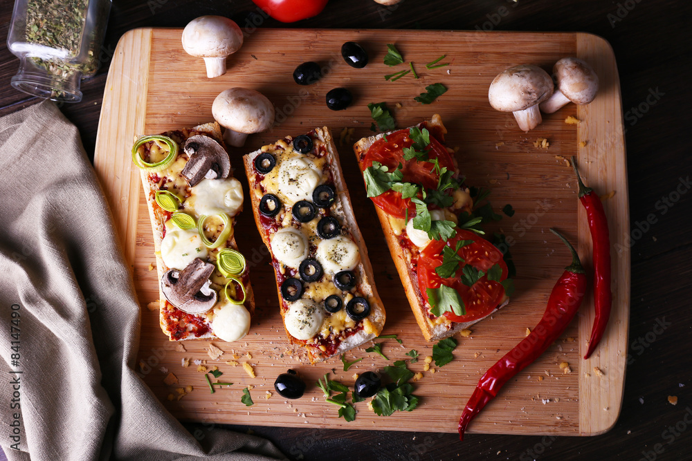 Different sandwiches with vegetables and cheese on cutting board on table close up