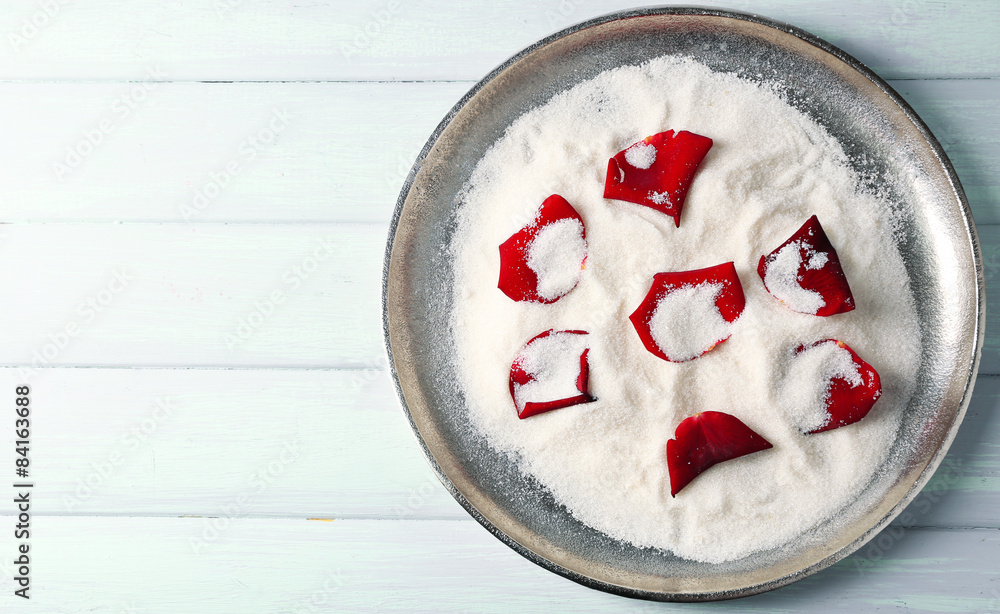 Candied sugared roses petals on tray, on wooden background