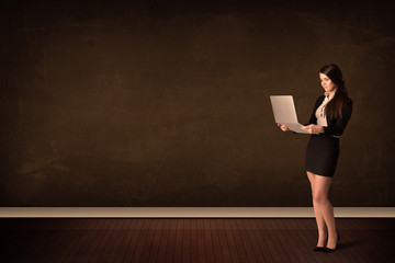 Canvas Print - Businesswoman holding high tech laptop on background with copysp