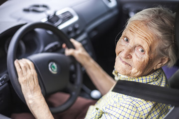 Wall Mural - Cheerful senior woman driving a car 