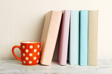 Sticker - Books and cup on wooden shelf on wallpaper background