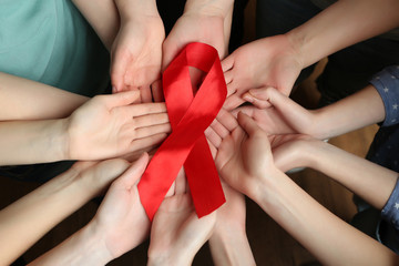 Wall Mural - Group of female hands with red ribbon as breast cancer awareness symbol, closeup