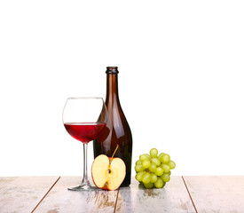 glass of red wine, a bottle of wine and grapes apple on board isolated on white background