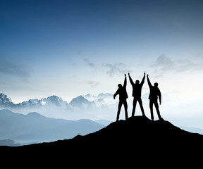 Wall Mural - silhouettes of team on mountain peak