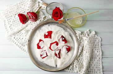 Making candied rose flower petals with egg whites and sugar, on wooden background