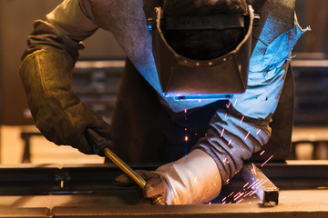 Wall Mural - Young man welding inside in a factory