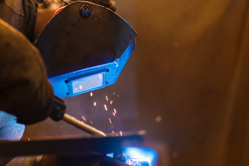 Wall Mural - Young man welding inside in a factory