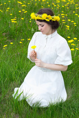 beautiful woman in white vintage dress with flower wreath sittin