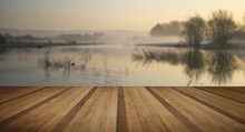 Landscape Of Lake In Mist With Sun Glow At Sunrise With Wooden P