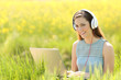 © Antonioguillem - Woman with a laptop and headphones in a field