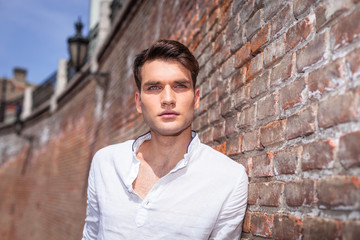 Handsome fashion man leaning on a brick wall