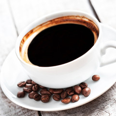 Poster - Coffee cup with roasted coffee beans over white wooden table