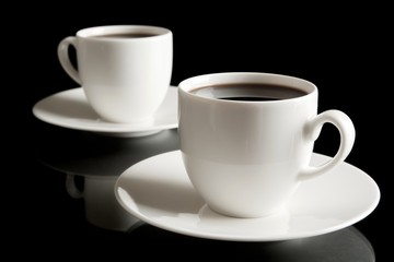 Wall Mural - Cups of coffee with saucer isolated on black