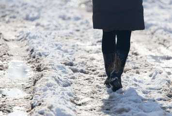 Wall Mural - girl in winter boots walking on snowy road