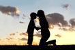 Silhouette of Mother Lovingly Kissing Little Child at Sunset