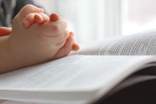 Young Christian Child's Hands Praying On Holy Bible