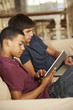 © Monkey Business - Two Teenage Boys Sitting On Sofa At Home Using Tablet Computer And Laptop