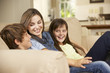 © Monkey Business - Mother And Two Children Sitting On Sofa At Home Watching TV Together