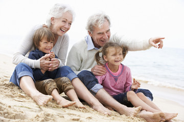 Grandparents And Grandchildren Sitting On Beach Together