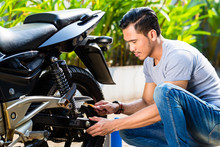 Asian Man At Motorcycle Maintenance