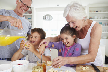 Wall Mural - Grandparents With Grandchildren Making Breakfast In Kitchen