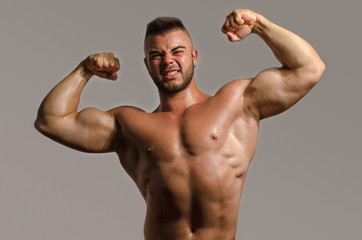 Bodybuilder topless, flexing his big biceps. Strong man with perfect abs, shoulders,biceps, triceps and chest