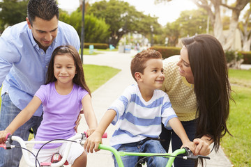 Wall Mural - Parents Teaching Children To Ride Bikes In Park