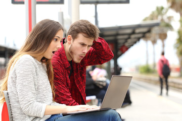 Wall Mural - Couple surprised watching a laptop in a train station