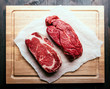 Raw steaks on chopping board