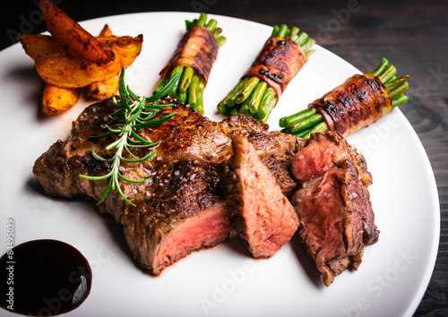 Juicy rib-eye steak with potatoe wedges and french beans Plakat