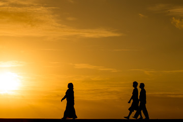 Wall Mural - Silhouette people walking at sunset