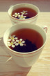 Two cups of tea and spring flowers on a wooden background