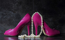 Ladies Pink High Heels With Long Strand Of White Pears Against A