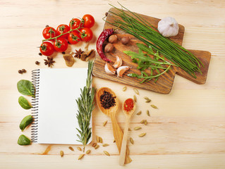 Open recipe book with fresh herbs, tomatoes and spices on wooden background