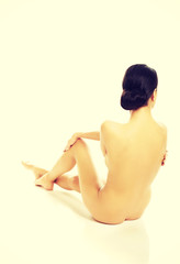 Sticker - Back view of nude woman sitting, holding her knee