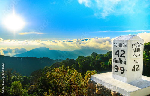 Fotografering Milestone at the roadside with mountain landscape