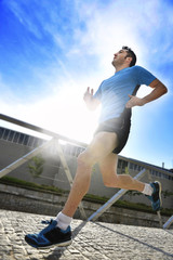 healthy sport man with athletic legs running in urban city park 