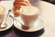 Cappuccino with croissant. Two cups of coffee on table