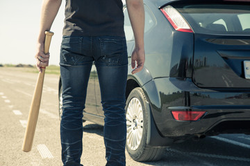 Man with baseball bat in the car on the road