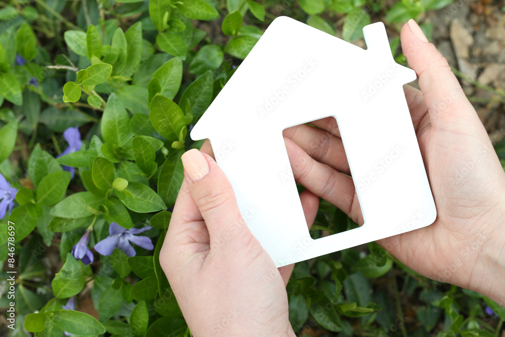 Female hands holding toy house outdoors