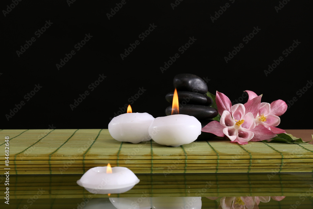 Spa still life with flowers and candlelight on black background